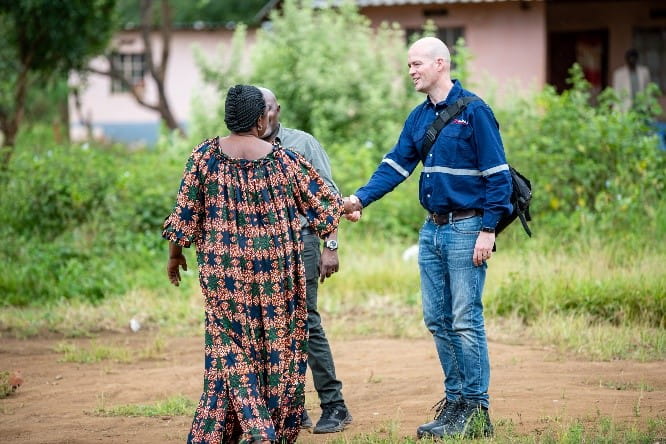 A man in jeans is shaking hands with a woman in a long dress